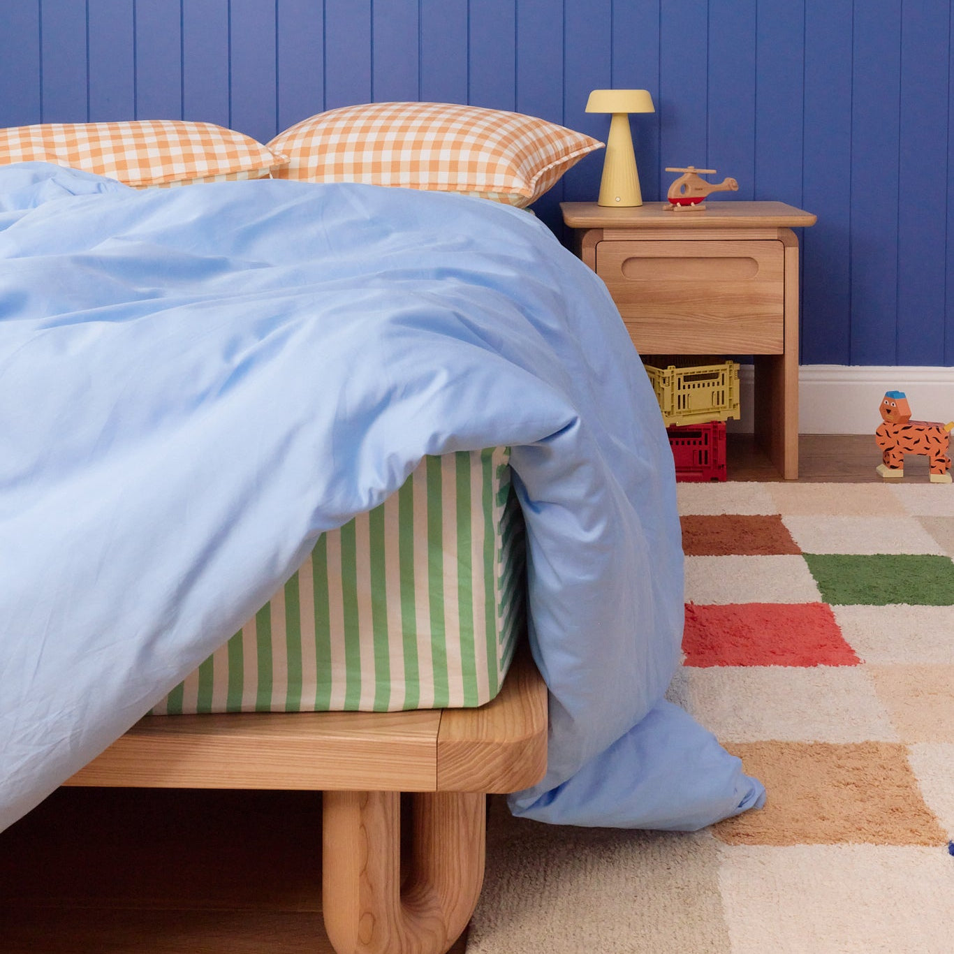 Children's bedroom with blue walls, wooden bed, and colorful rug.